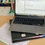 ordenador portátil con código de programación y apuntes